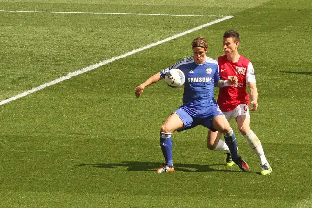 Si Fernando Torres na naka-asul na Chelsea kit habang kinokontrol ang bola at nasa likuran niya si Laurent Koscielny.